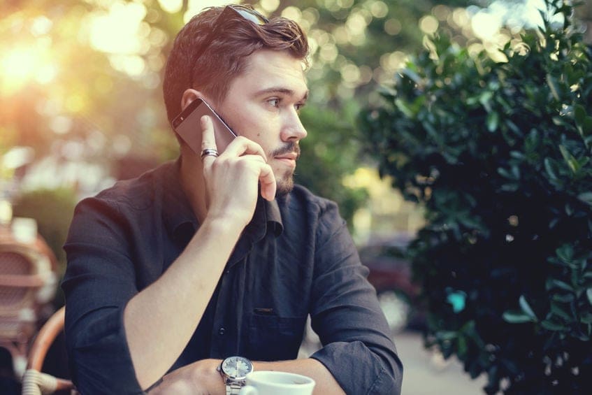 a man sitting at a table talking on a cell phone