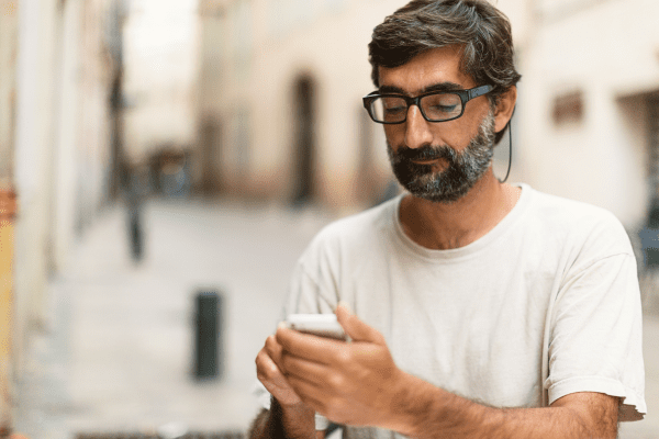 a man with a beard is looking at his cell phone