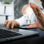 a man holding a light bulb over a laptop