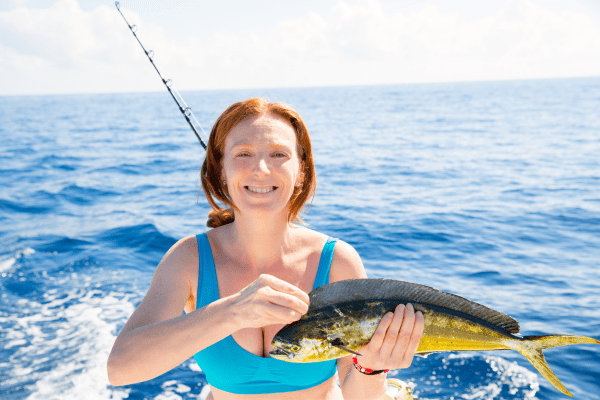 a woman holding a fish on a boat