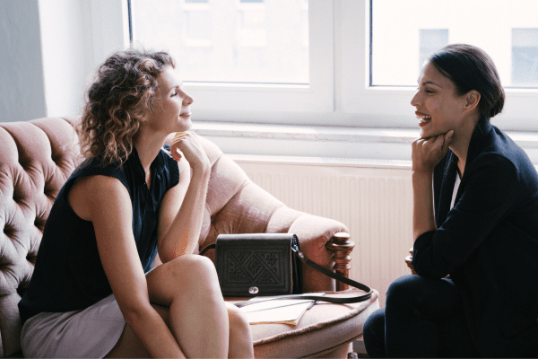 two women sitting on a couch talking to each other