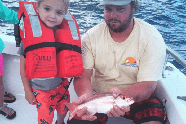 a man and two children on a boat holding a fish