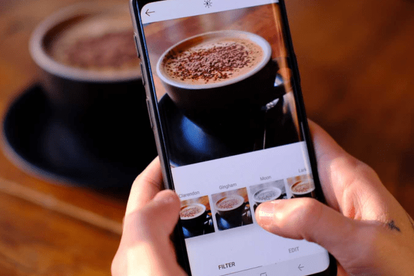 a person taking a picture of a cup of coffee