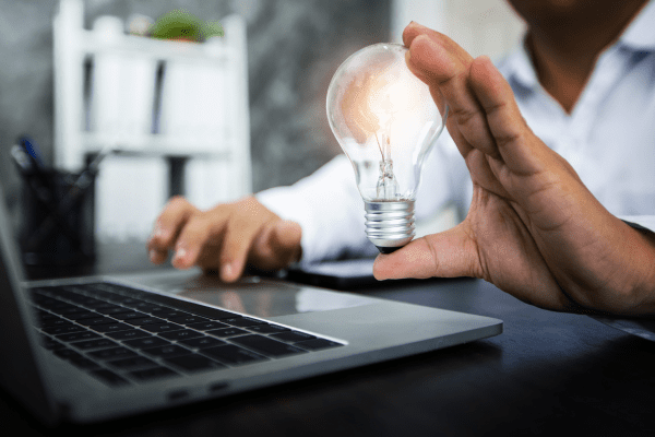 a man holding a light bulb over a laptop